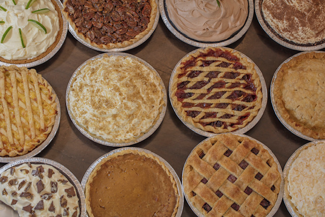 Assorted pies from Lucy’s Pie House & Grill arranged on a wooden surface, showcasing various flavors and crusts